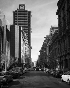 A Joburg city centre street, lined with parked cars on both sides, with the e.tv building in the background.