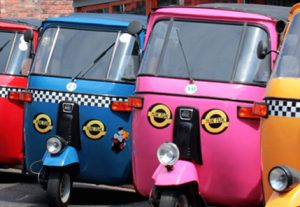 A row of colourful tuk-tuk, three-wheel vehicles.
